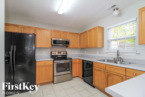 A kitchen with wooden cabinets and a black refrigerator.