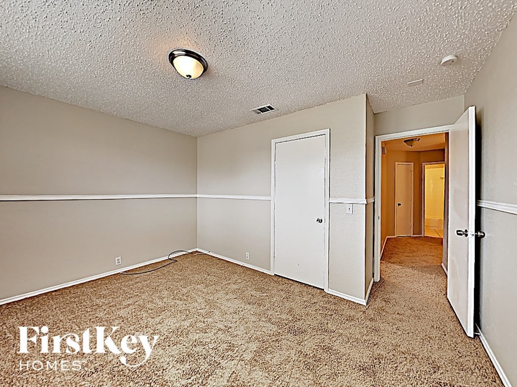 an empty bedroom with a door to a closet