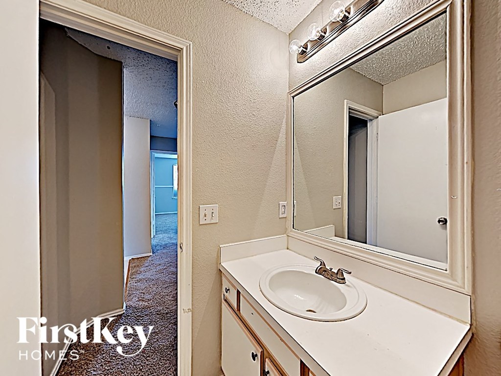 a bathroom with a sink and a mirror and a doorway