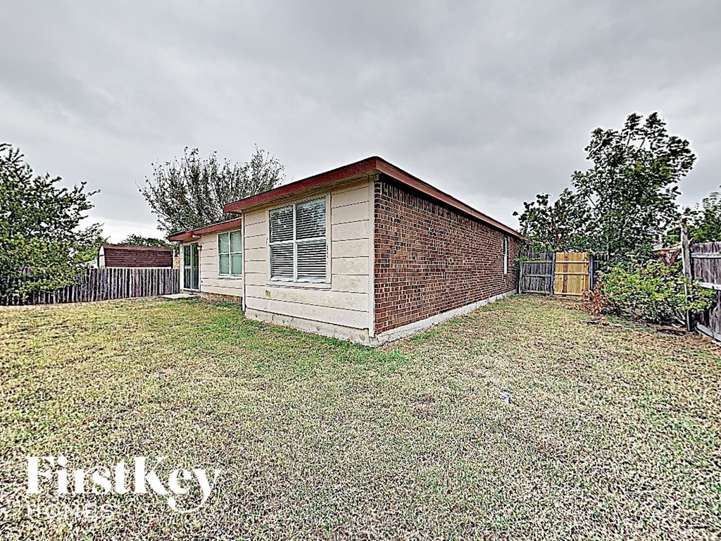 the backyard of a small brick house with a fenced in yard