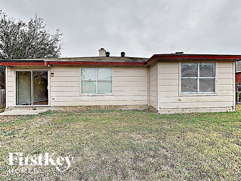 a small white house with a yard and a cloudy sky