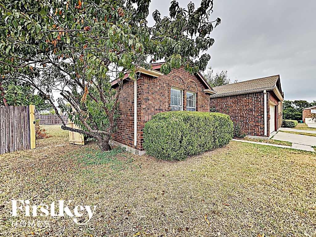 a small brick house with a tree in the yard