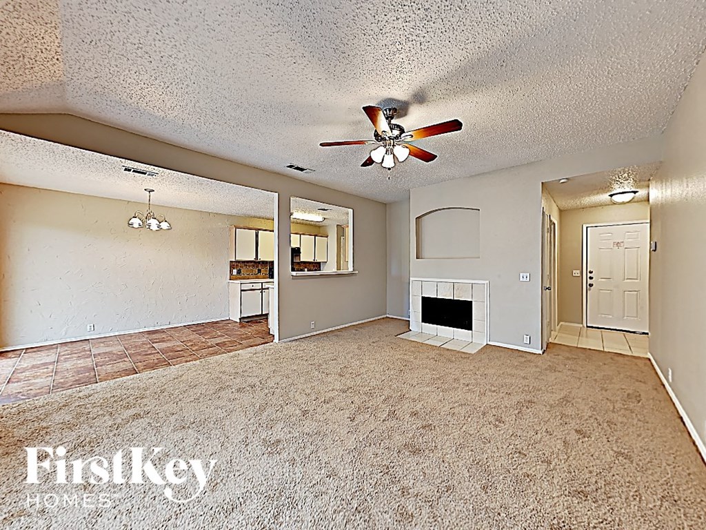 an empty living room with a ceiling fan and a fireplace