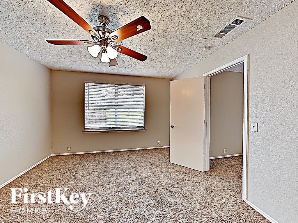 an empty room with a ceiling fan and a window