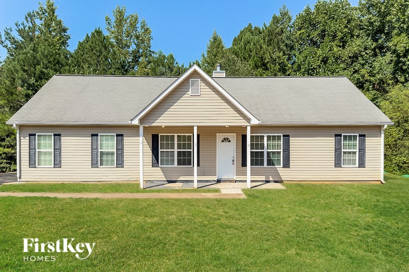 a white house with a lawn and trees in the background