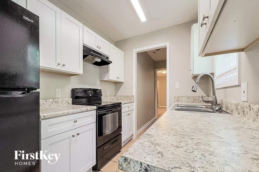 a kitchen with white cabinets and black appliances