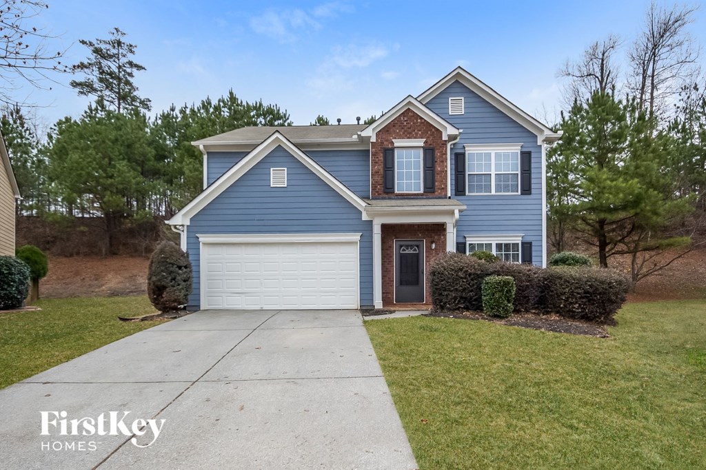 A blue house with a garage door and a driveway in front.