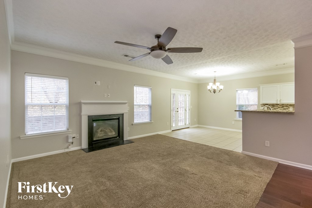 A spacious living room with a fireplace and a ceiling fan.