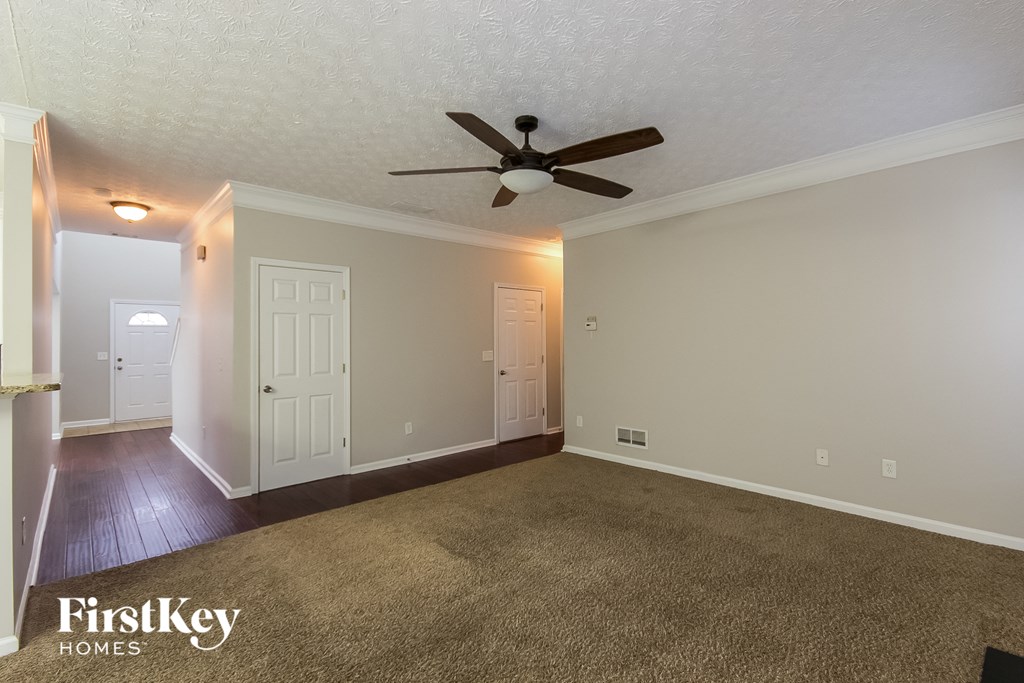 A spacious room with a carpeted floor and a ceiling fan.