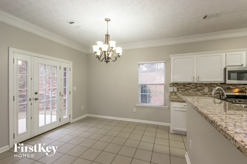 A kitchen with a chandelier and a dining area with a table and chairs.