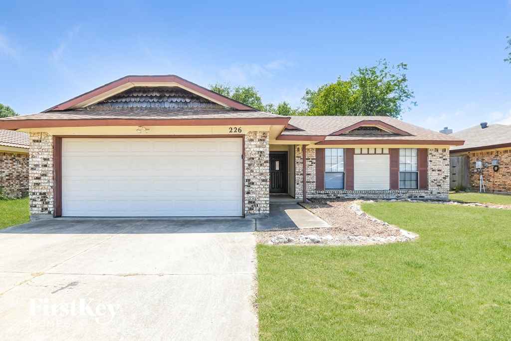 a brick house with two garage doors and a lawn