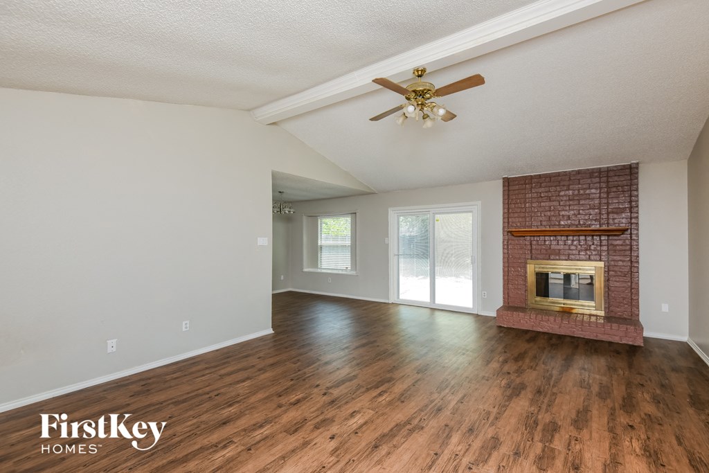 a living room with a brick fireplace and a ceiling fan