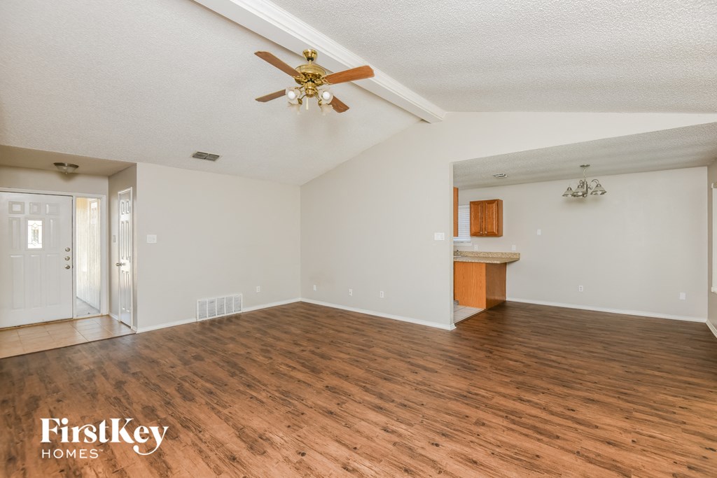 an empty living room with wood flooring and a ceiling fan