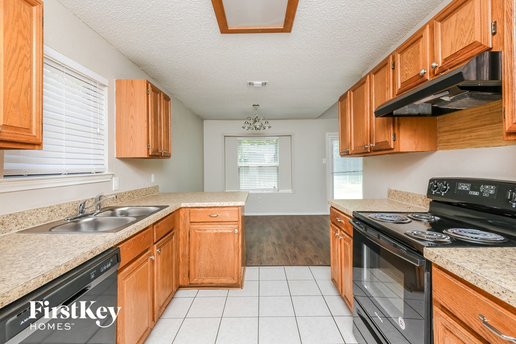 a kitchen with wooden cabinets and black appliances and white flooring