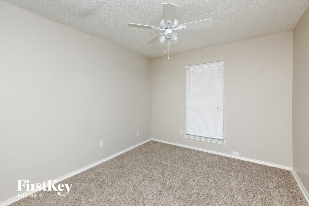 an empty room with a ceiling fan and a window