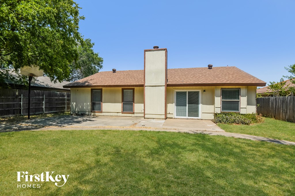 a small yellow house with a yard and a fence