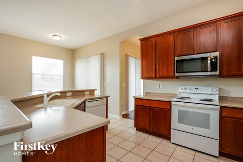 full view of kitchen with white appliances and wooden cabinets