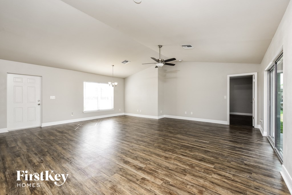 an empty living room with wood floors and a ceiling fan