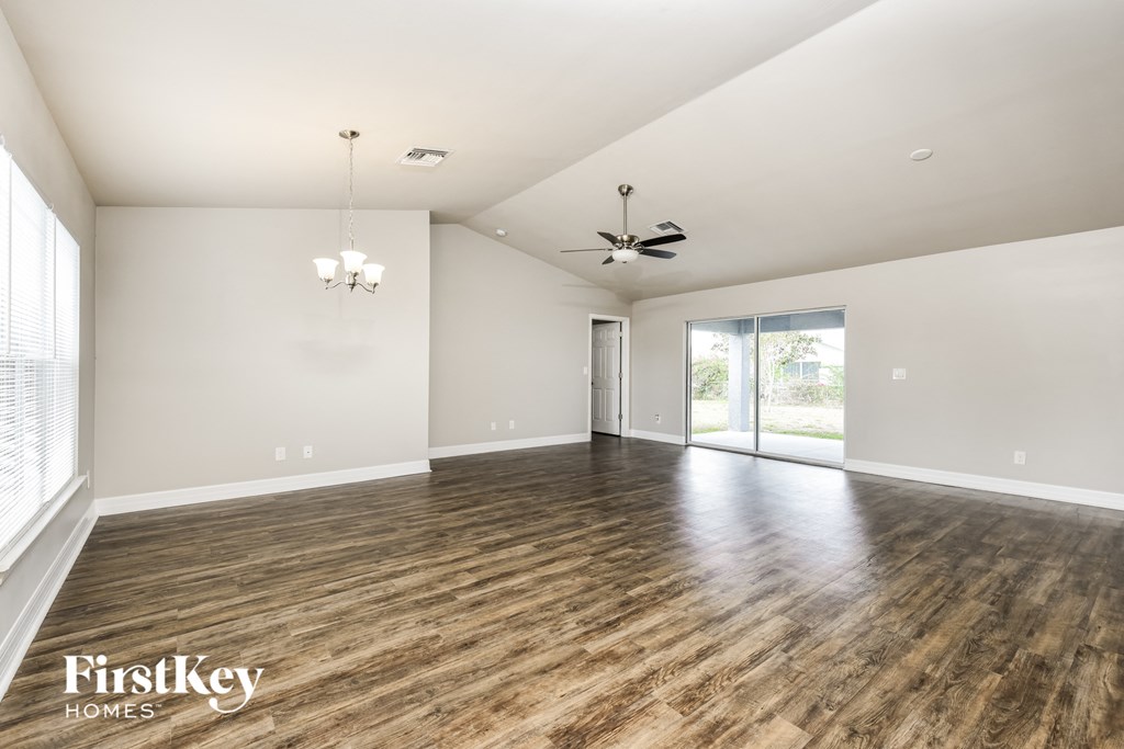 an empty living room with wood flooring and a ceiling fan