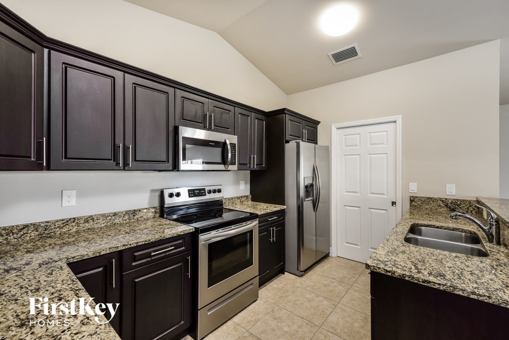 a kitchen with granite counter tops and black cabinets and stainless steel appliances