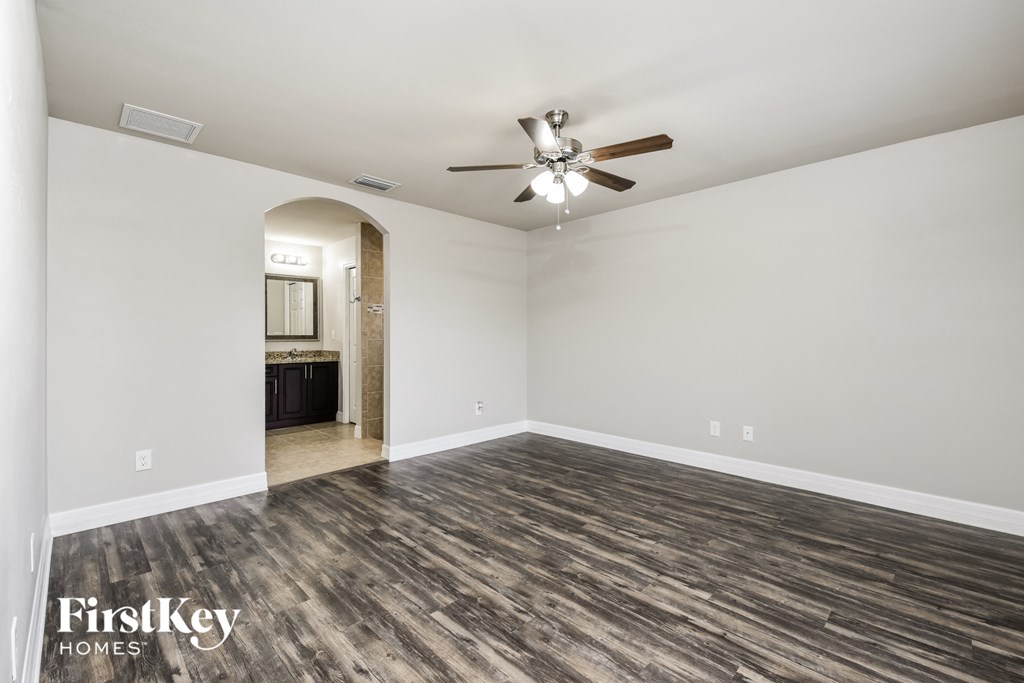 an empty living room with wood flooring and a ceiling fan