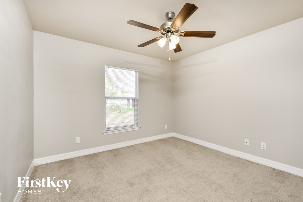 an empty room with a ceiling fan and a window
