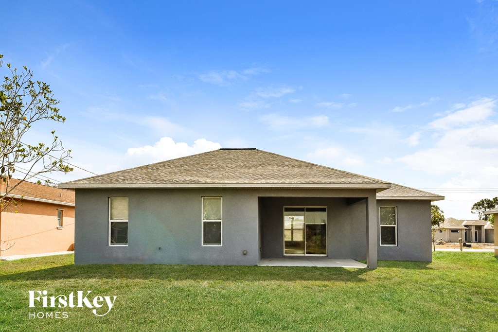 a small gray house with a lawn and a blue sky