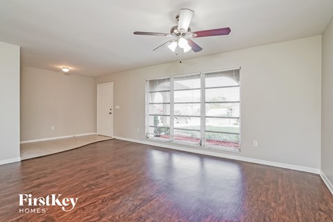 A room with a ceiling fan and wooden flooring.