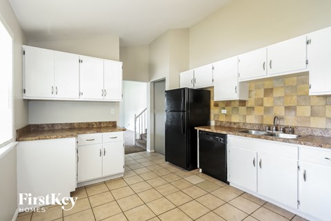 A kitchen with white cabinets and a black refrigerator.
