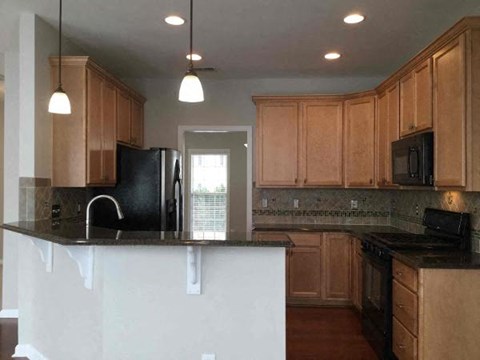 A kitchen with wooden cabinets and black appliances.