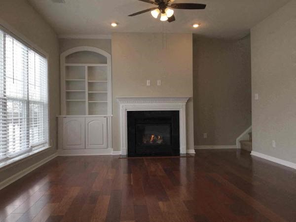 A living room with a fireplace and a fan.