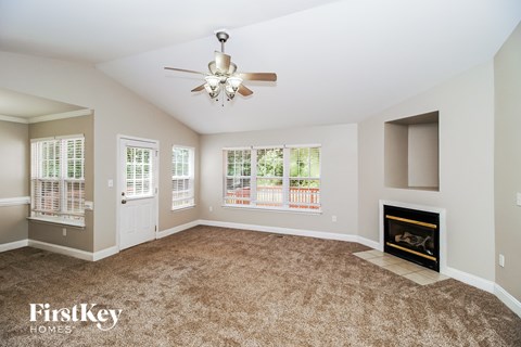 A spacious living room with a fireplace and a ceiling fan.