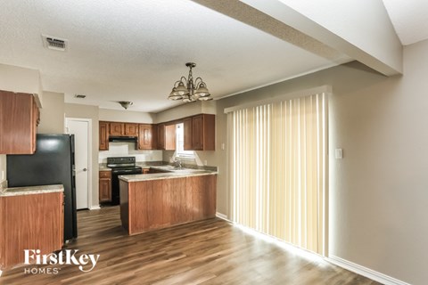 A kitchen with wooden cabinets and a black fridge is shown.