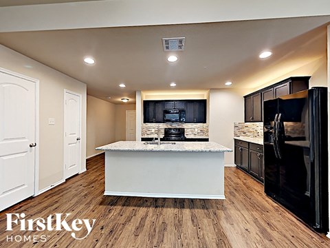 A kitchen with a white island and black appliances.