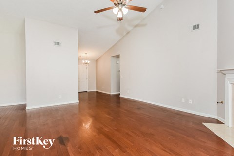 A spacious room with wooden floors and a ceiling fan.