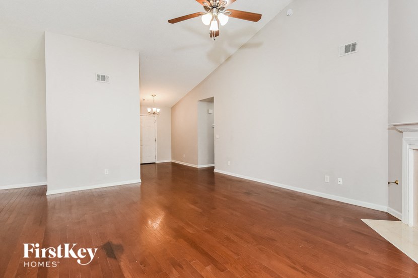 A spacious room with wooden floors and a ceiling fan.