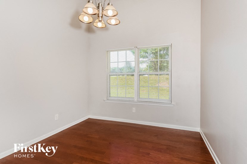 A room with a wooden floor and a window with blinds.