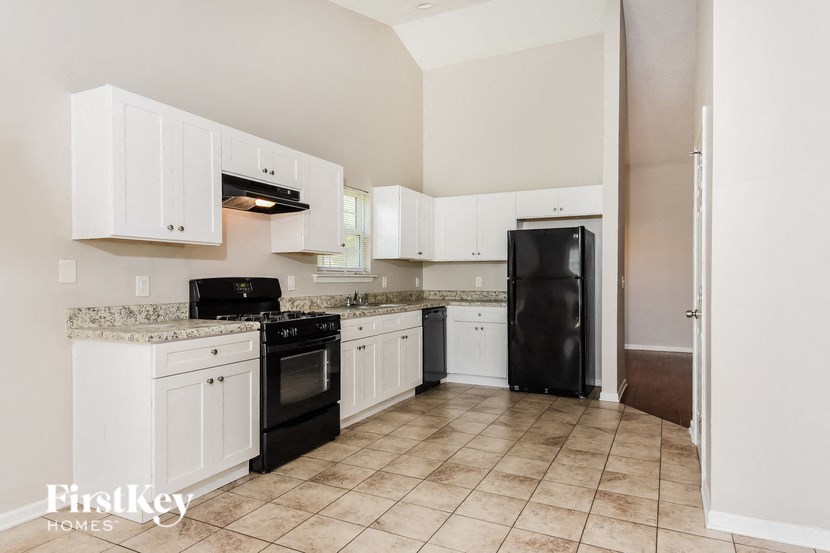 A kitchen with white cabinets and black appliances.