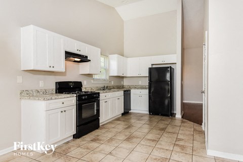 A kitchen with white cabinets and black appliances.