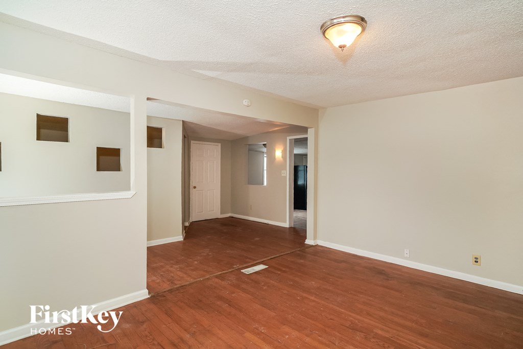 an empty living room with wood floors and white walls