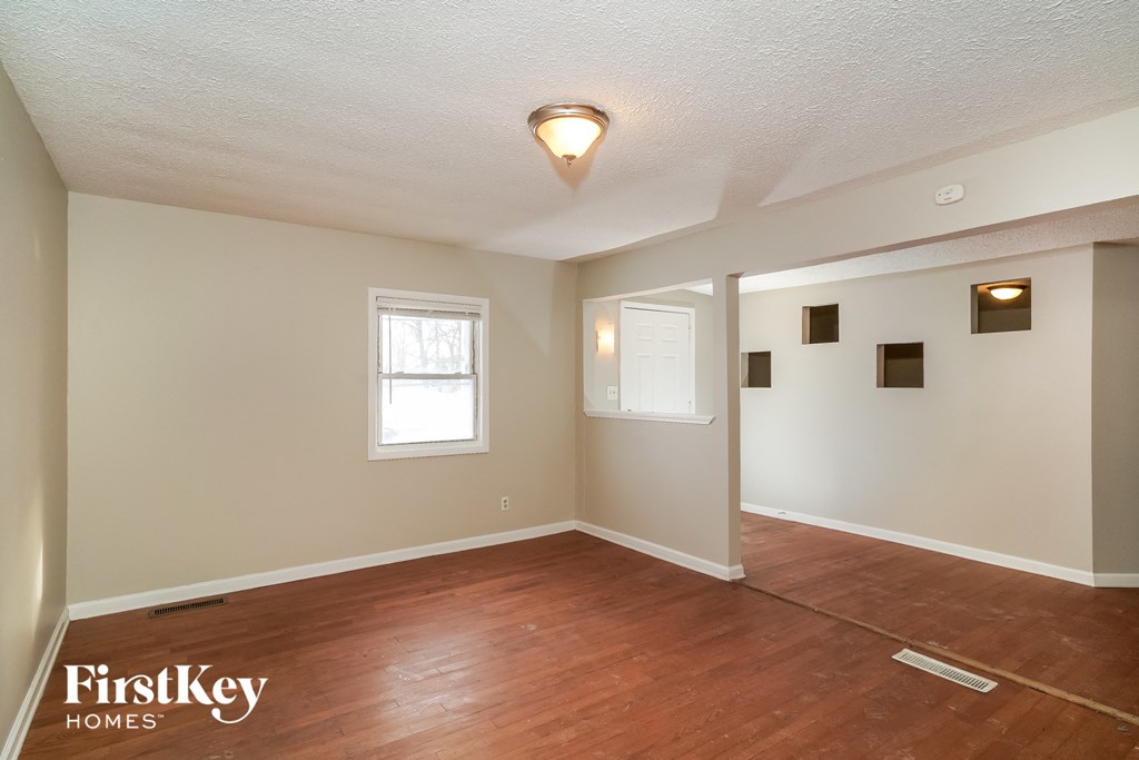 the living room and dining room of a house with wood floors and white walls