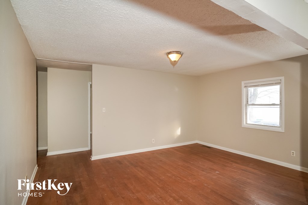 the living room of an empty house with wooden floors and a window