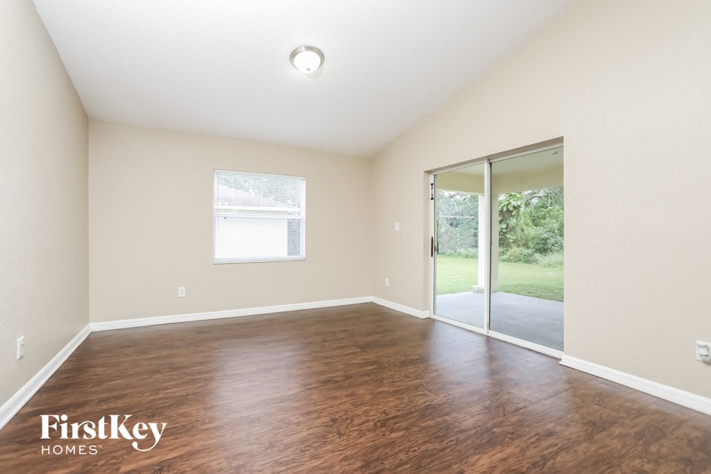 A room with wooden flooring and a sliding glass door leading to a backyard.