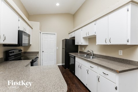 A kitchen with white cabinets and a black fridge.