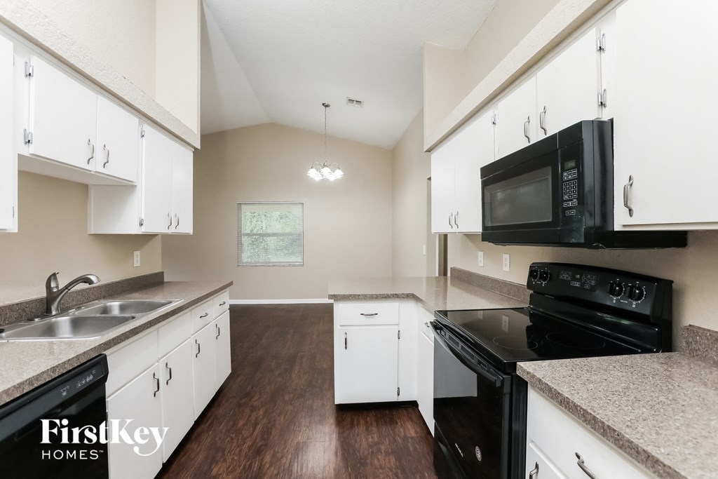 A kitchen with white cabinets and black appliances.