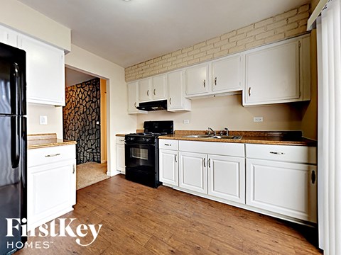 a kitchen with white cabinets and black appliances and a wooden floor