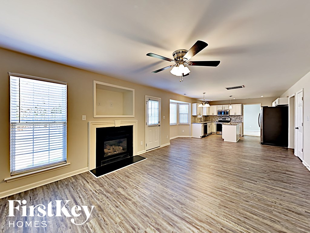 A spacious room with a fireplace and a ceiling fan.