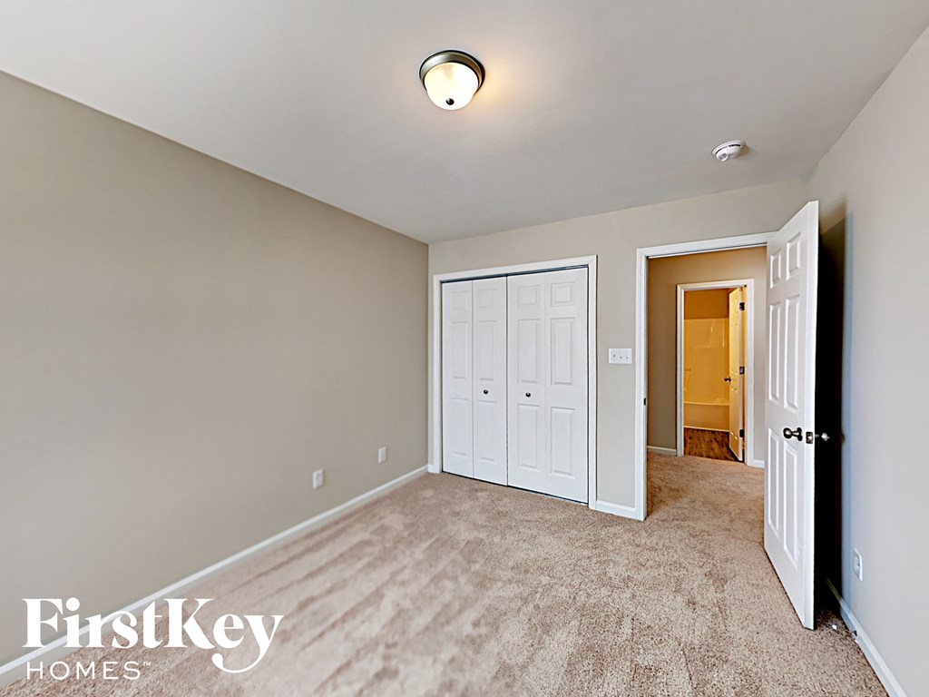 A bedroom with a carpeted floor and a white door.