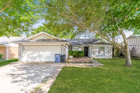 a white house with a white garage door and a tree