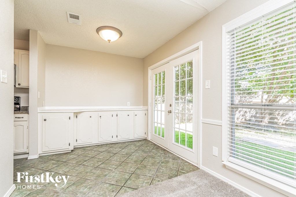a kitchen with white cabinets and windows and a tiled floor